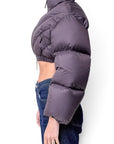 Lost Labels Khaite cropped puffer jacket in dark grey worn with blue jeans, side profile view