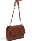 Lost Labels Chanel brown leather flap bag with diagonal quilting and gold chain strap held by hand