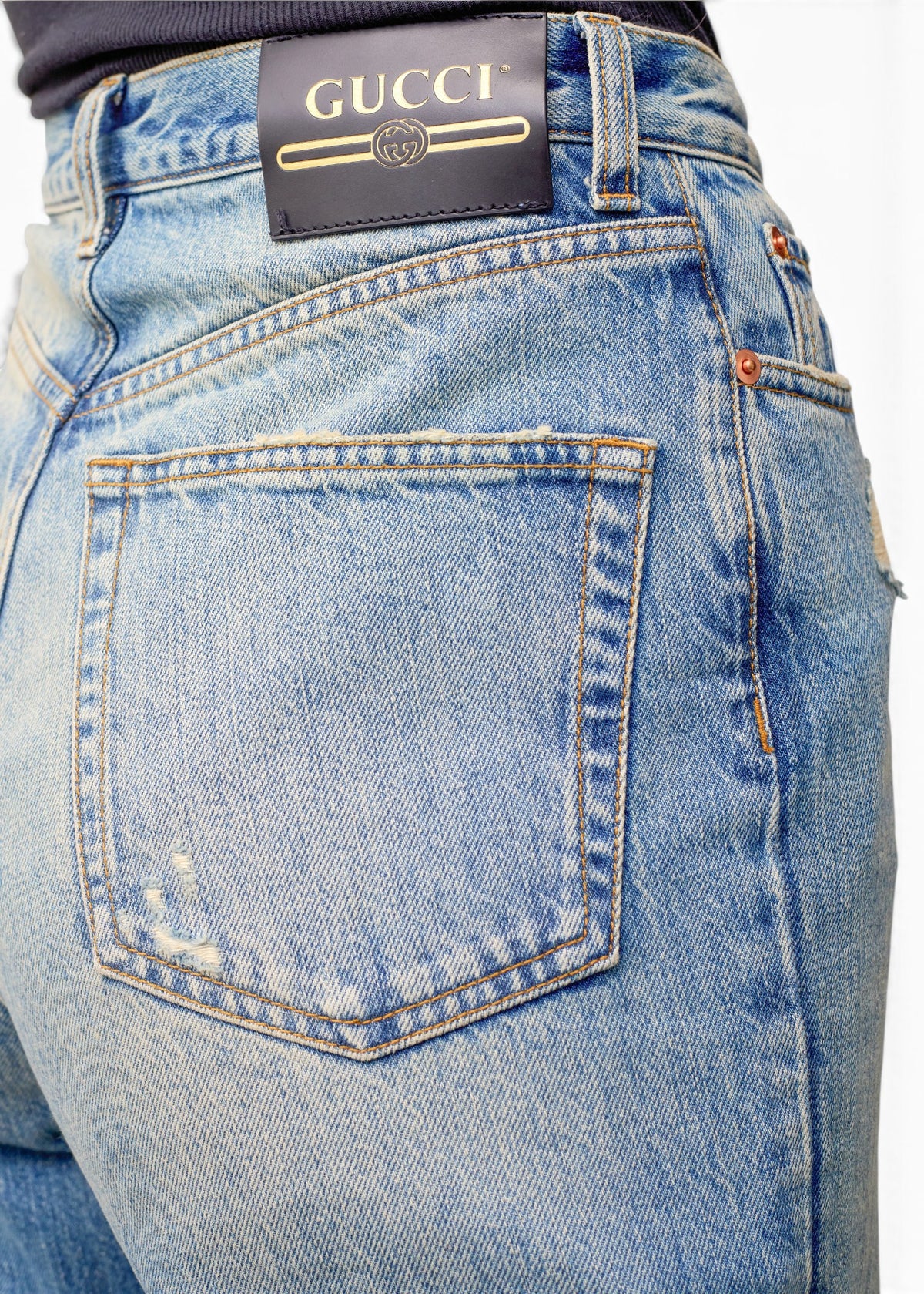 Lost Labels Gucci light wash denim jeans featuring a black leather logo patch on the back waistband
