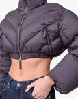 Lost Labels Khaite cropped puffer jacket in dark grey with chevron quilting, high collar, and silver zip closure.