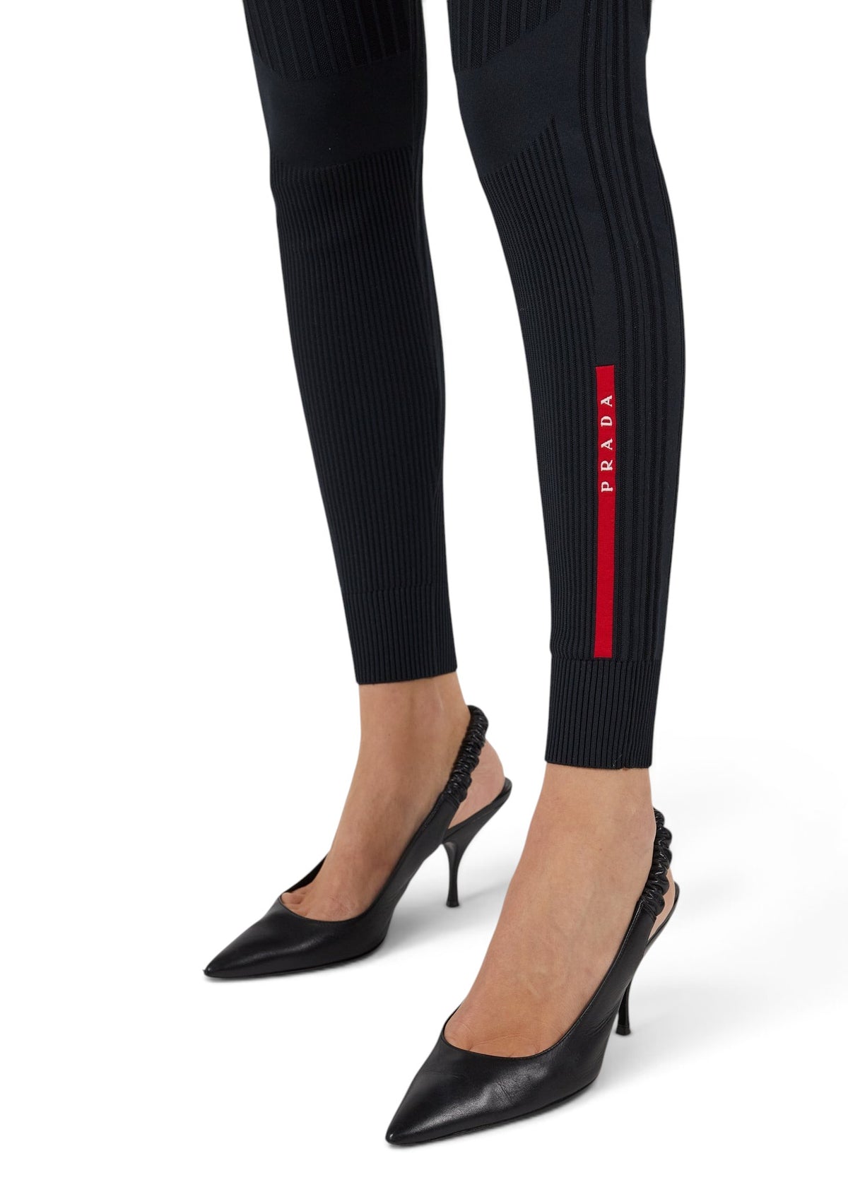 Lost Labels Prada black ribbed tights featuring a vertical red logo stripe on the lower leg worn with black heels.
