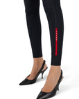 Lost Labels Prada black ribbed tights featuring a vertical red logo stripe on the lower leg worn with black heels.