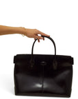 Lost Labels vintage Tod's black leather handbag held by a hand with a gold bracelet against a white background