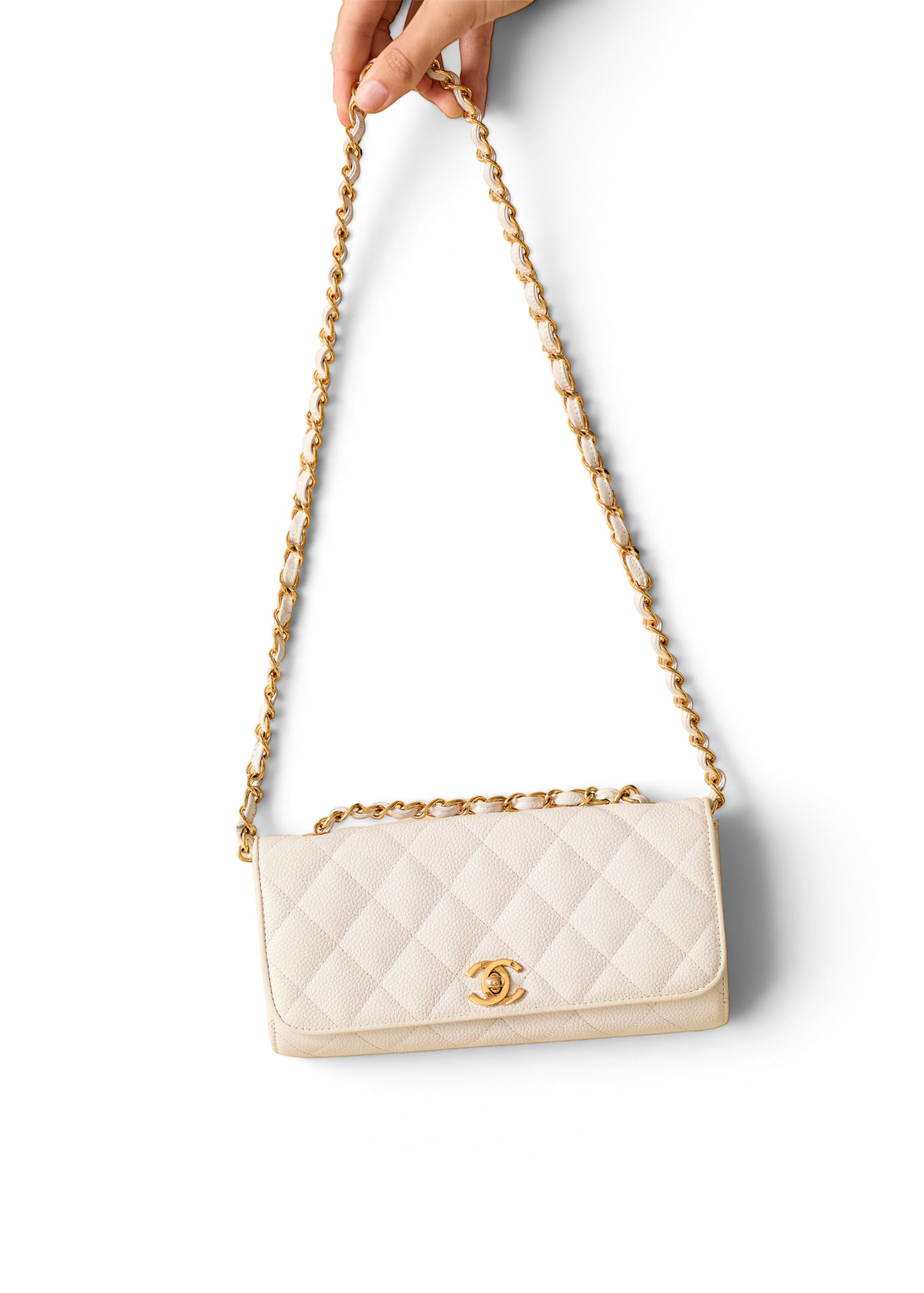 Lost Labels white quilted Chanel bag with gold chain strap held by hand against a white background